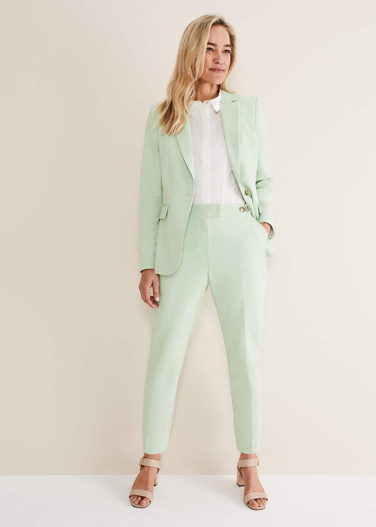 Woman wearing light pink suit co-ord with silver clutch and heels