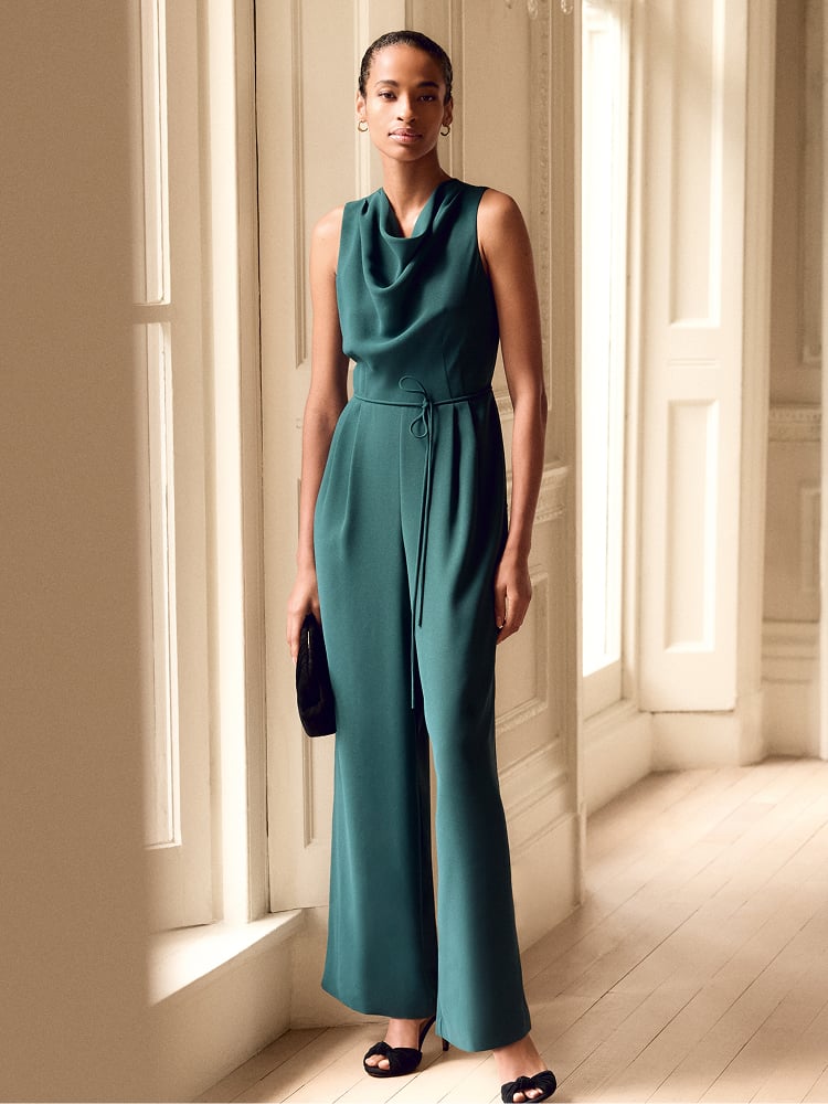 Woman wearing a teal Phase Eight jumpsuit in a hallway