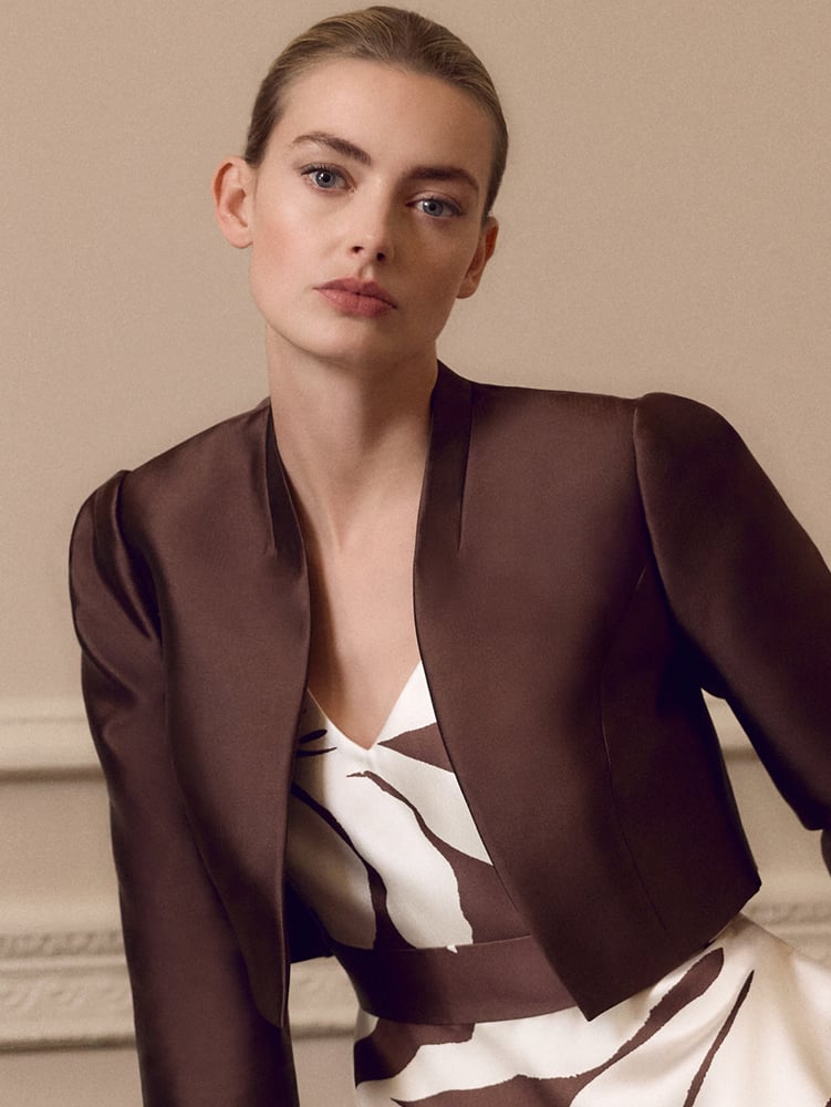 Woman wearing a cropped jacket and fascinator over a printed Phase Eight outfit