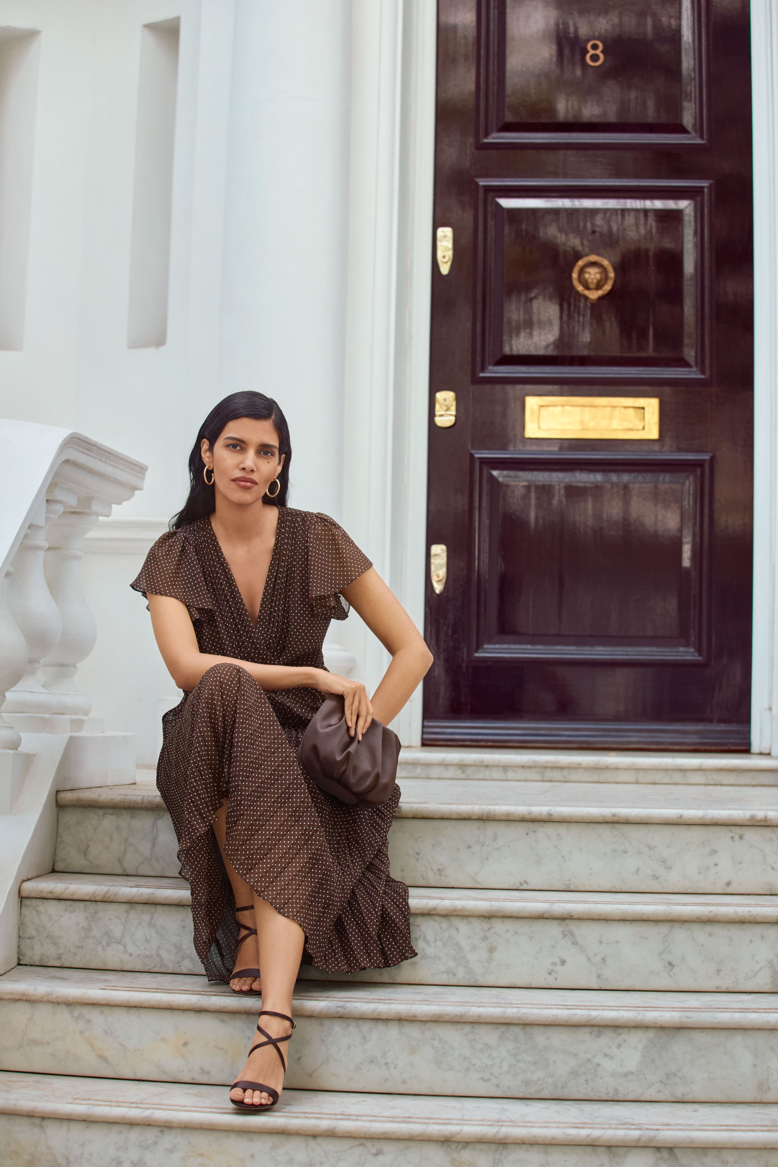 A woman wearing the Louisa pin spot chocolate wrap dress.