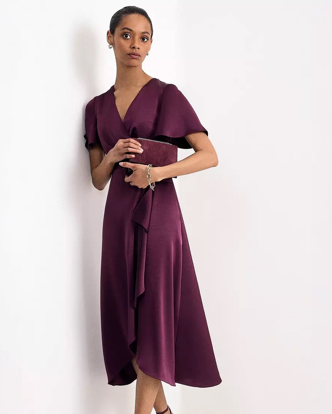A woman wearing a Hobbs satin wrap midi dress in berry.
