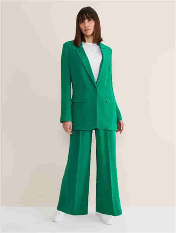 Woman wearing green blazer and green suit trousers
