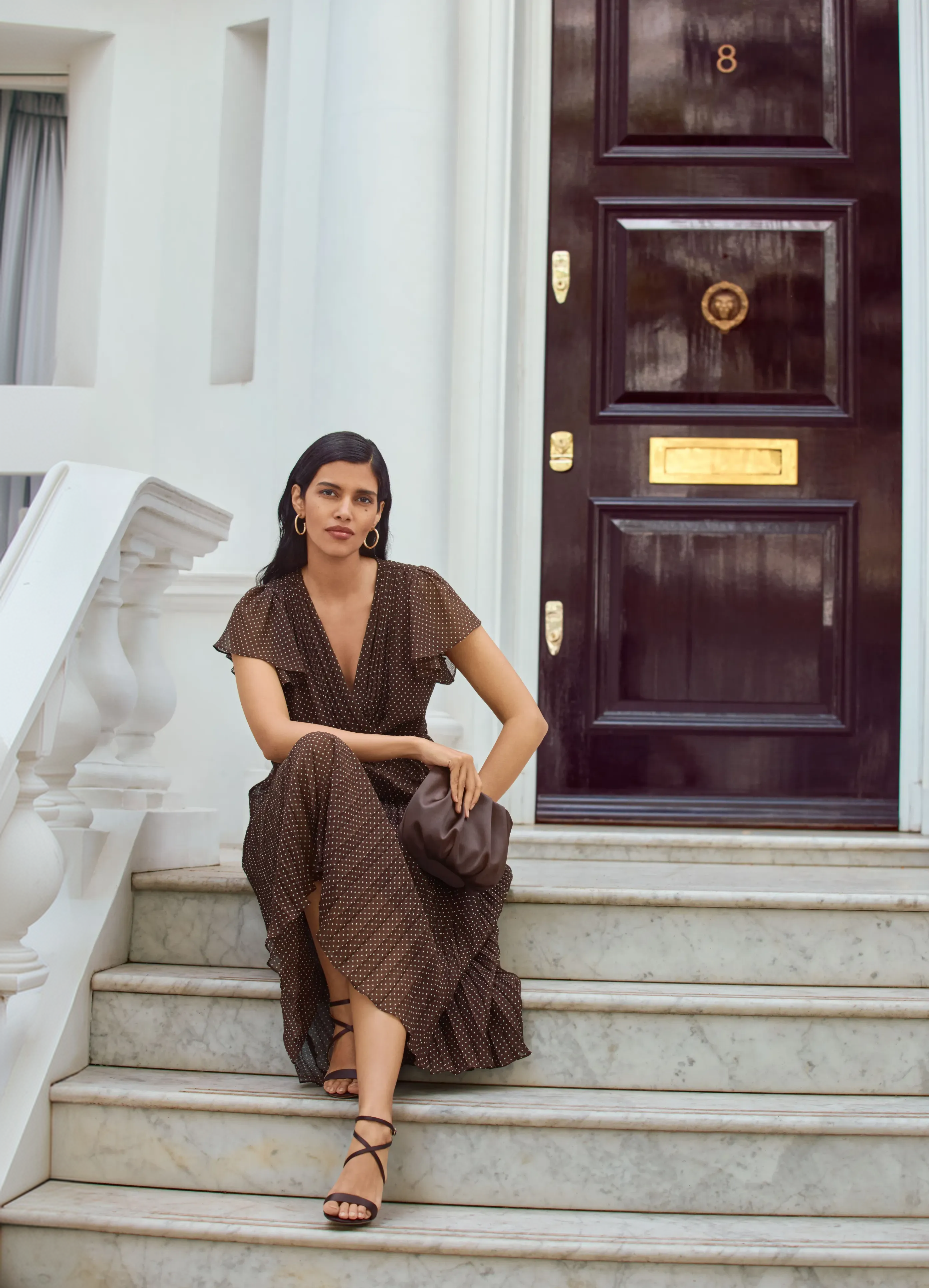 A woman wearing the Louisa pin spot chocolate wrap dress.