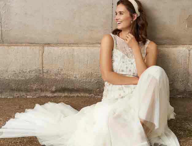 Woman sitting down modelling white beaded wedding dress