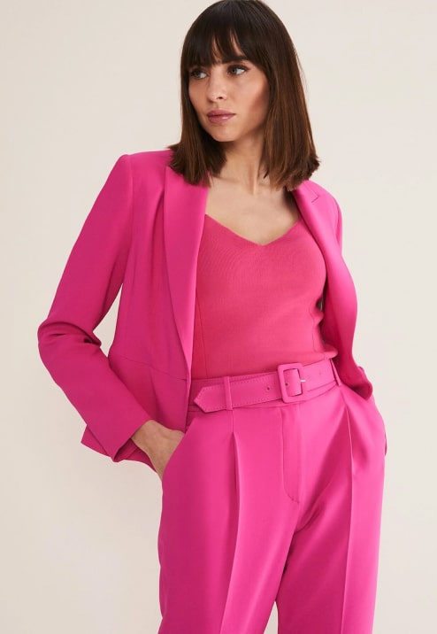 Woman wearing pink suit co-ord and pink knitted top