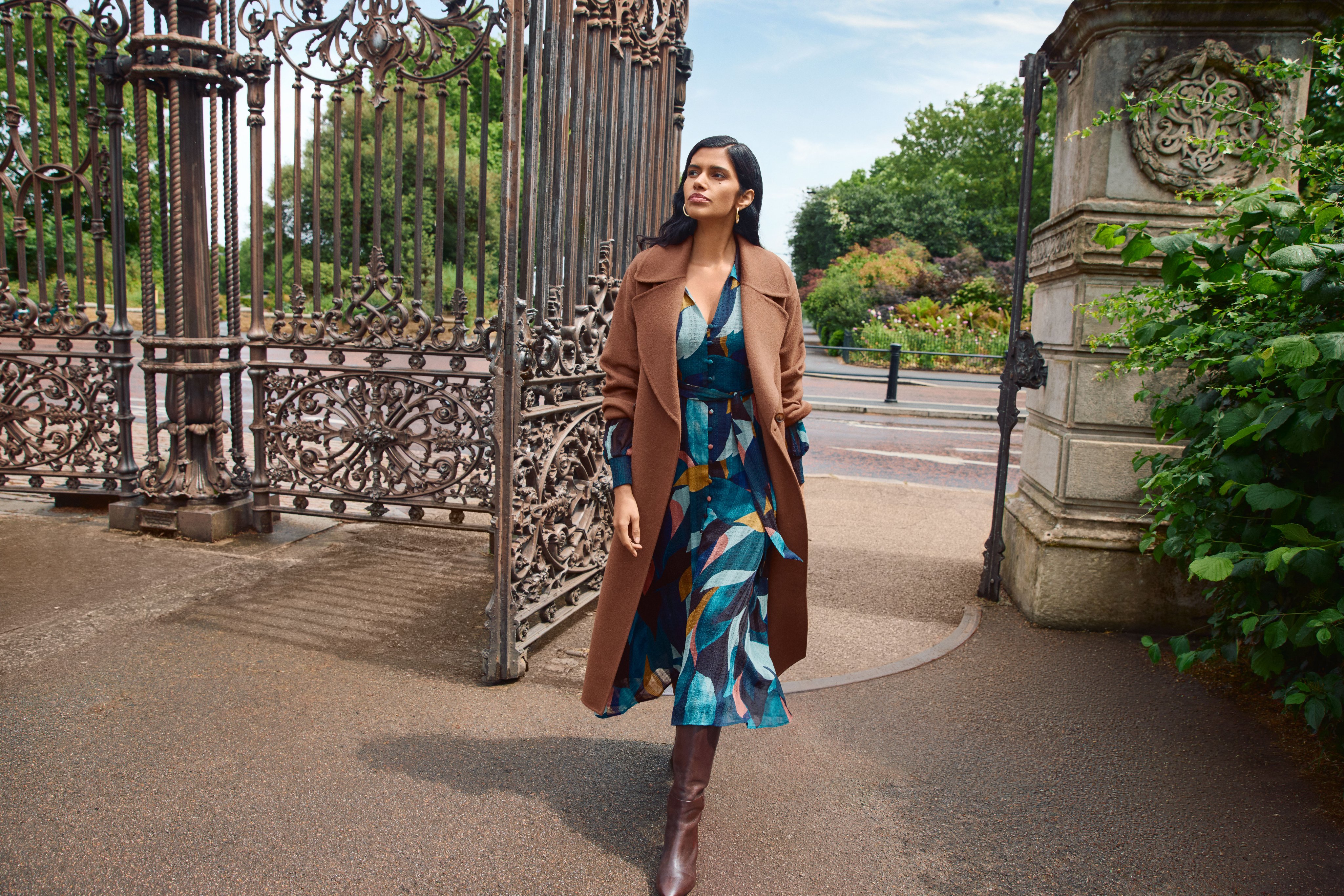 A woman wearing the Catalina petal print dress with the Daisy shawl collar coat.