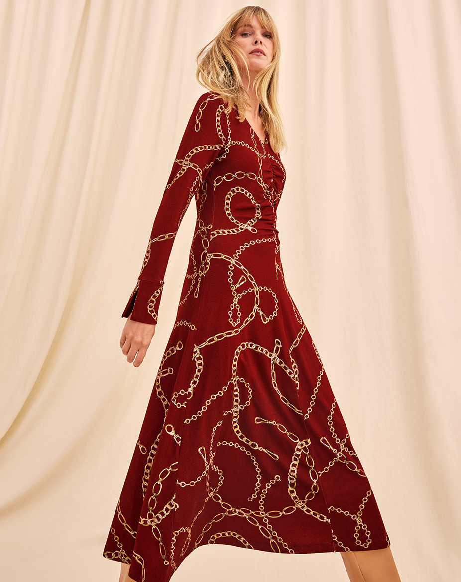 Woman striding in a deep red midi dress with a chain print
